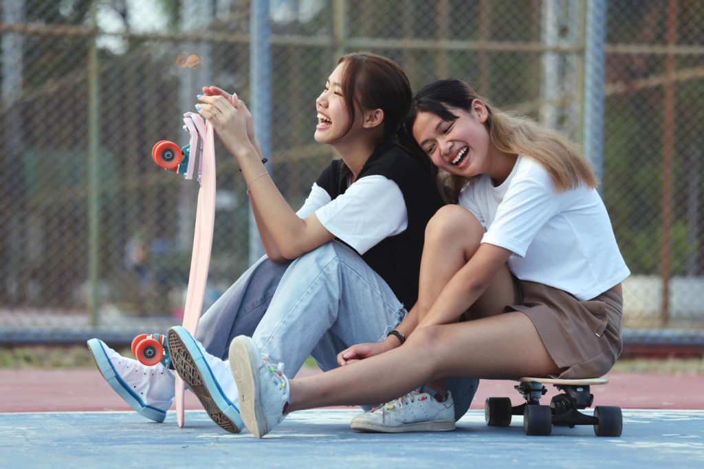 Two young girls with skateboards playing together.
