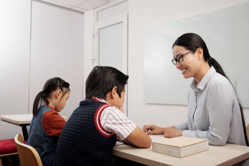 two students sitting classroom with a teacher
