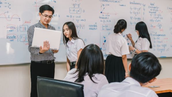 girl-looking-laptop-teacher-classroom